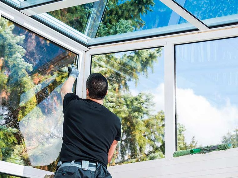 Hand mit Fensterwischer bei der Glasfassadenreinigung in Innsbruck